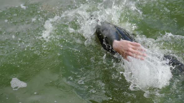 Slow Motion Pro Swimmer Triathlete in a Wetsuit Swims in Open Water an Athlete Trains Before a