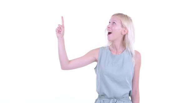 Happy Young Blonde Woman Pointing Up and Looking Excited