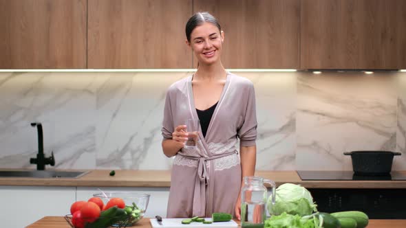 Happy Housewife Holding Glass of Pure Water Posing on Kitchen at Home