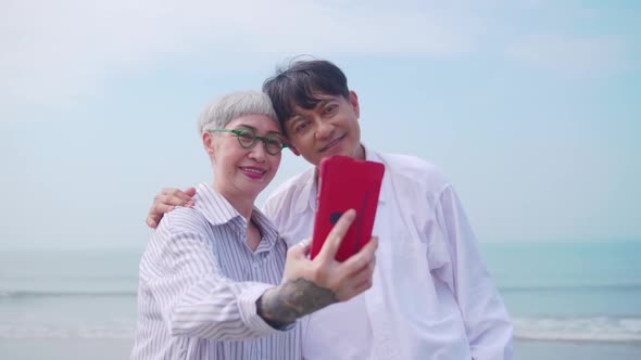 A senior woman taking a selfie photo with her partner on the beach.