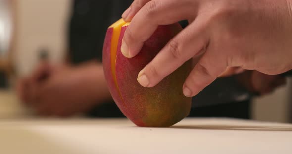 Person Cutting A Fresh Ripe Sweet Mango Using A Sharp Knife.  - close up shot