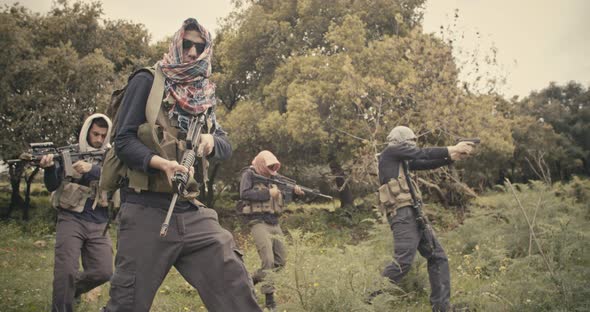 Squad of armed terrorists patrolling a forest area during combat