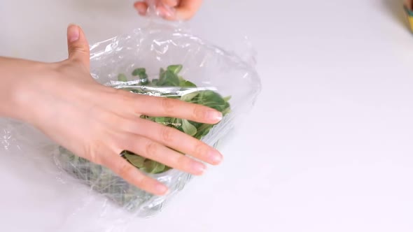 Woman Using Food Film for Food Storage on a White Table