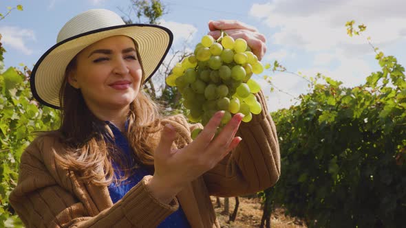 Winemaker Smilling Adult Woman with Hat Holding a Bunch of White Grape