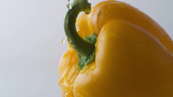 Water drops on rotating yellow pepper. Slow Motion. alt