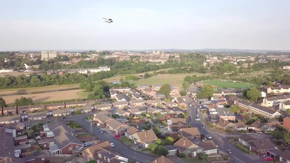 Aerial fly over of Exeter, England, with birds flying by, summer golden hour