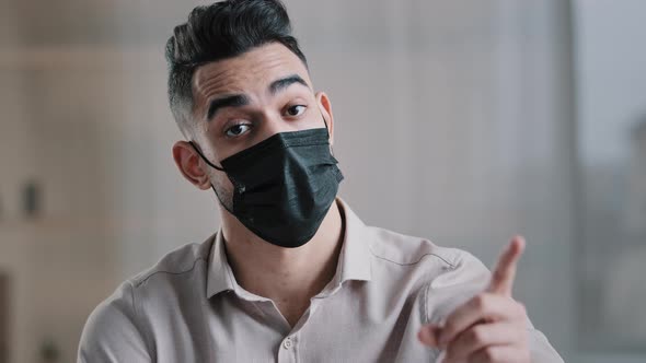 Arabian Businessman Employee Wear Medical Mask Sit at Office Desk Shakes Wave Index Finger Warn