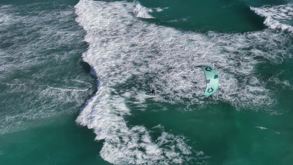 Kite surfer sailing in rough turquoise waves and windy African weather; drone