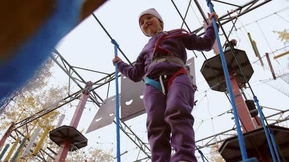 Little Girl Trying Take Step but Stumbles and Slides Off in Rope Park