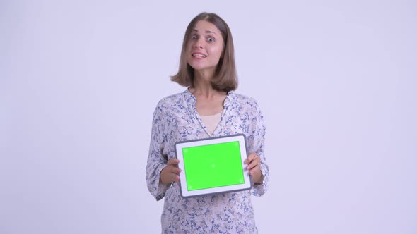 Happy Young Pregnant Woman Showing Digital Tablet and Looking Surprised