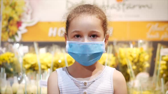 Little Girls Corrects a Mask From Viruses of the Epidemic of a Coronavirus or Viruses Looking at the