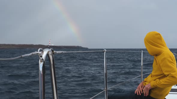 A Man in a Yellow Hoodie on a Yacht Looks at a Beautiful Rainbow Over the Canary Island of Tenerife