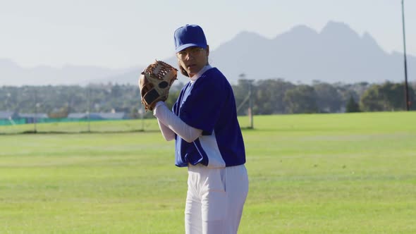 Caucasian female baseball player wearing glasses pitching ball on baseball field