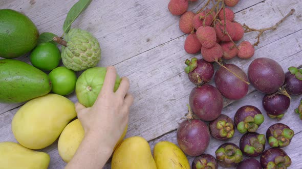 Woman Takes Away Fruits From a Wooden Table Full of Tropical Fruits