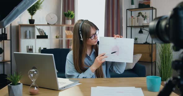 Girl in Headphones Recording Video on Camera while Explaining results