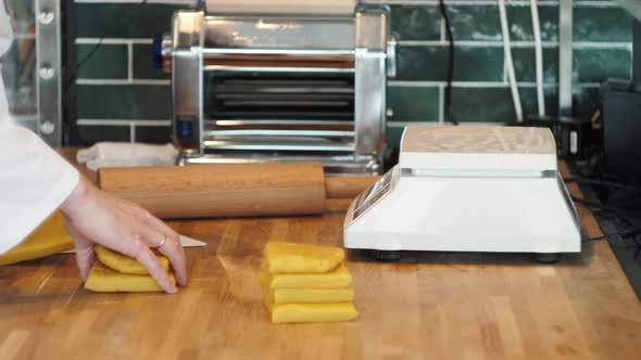 Chef Making Spaghetti Noodles and Lasagne Dough with Pasta Machine on Kitchen Table with Some