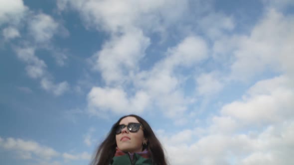 A Darkhaired Woman with Sunglasses is Walking Around