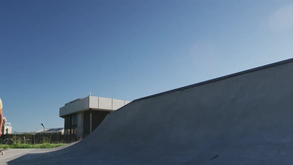 Caucasian man riding and jumping on skateboard on sunny day