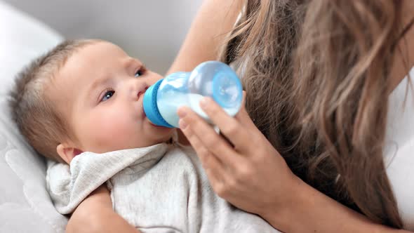 Closeup Adorable Little Baby Drinking Milk From Nipple Bottle Relaxing Lying on Female Hand