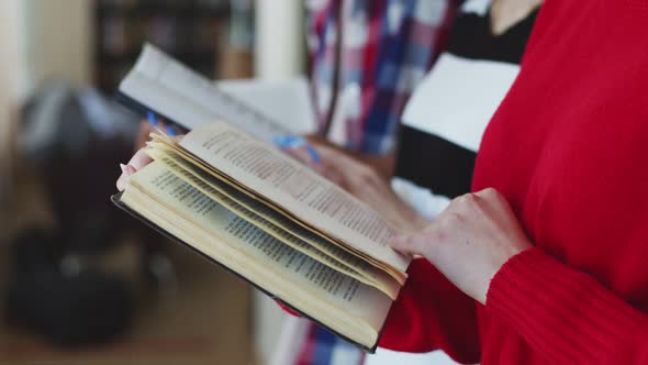 Women's beautiful hands flip through a textbook page, students read books preparing for the exam