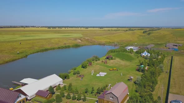 Wedding Venue on Green Field at Calm Lake Aerial View