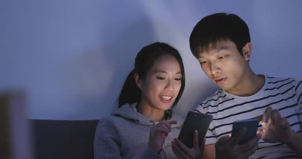 Husband and wife using cellphone at home