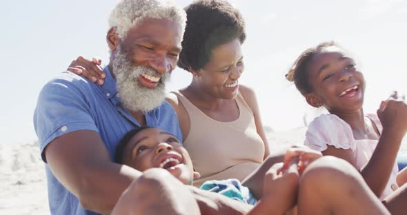 Happy african american couple embracing with children on sunny beach