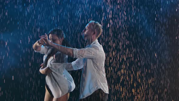 Passionate Movements of a Couple Dancing Salsa Among Glittering Raindrops and Studio Lights. A Dance