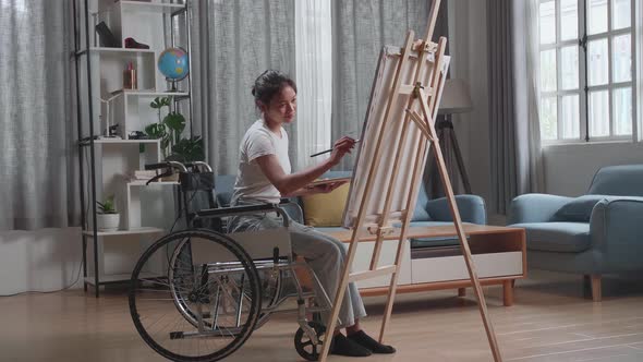 Asian Artist Girl In Wheelchair Holding Paintbrush Mixed Colour And Thinking Before Painting