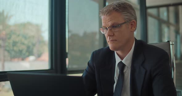 Close up of a businessman looking at a laptop screen, working at the office, Slow motion