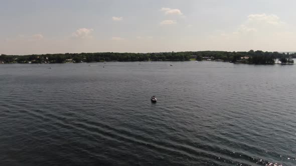 Aerial view circling boat in the middle of a lake during summer, 4k drone footage