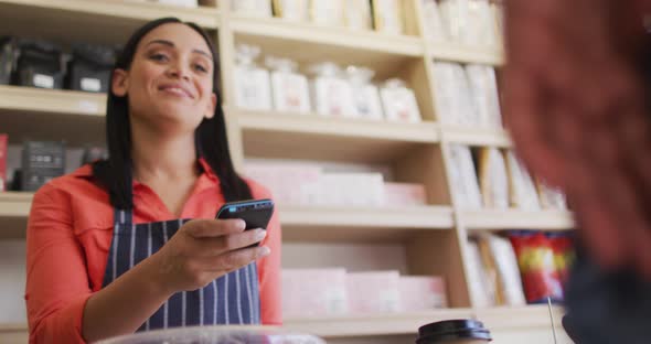 Video of hands of biracial man paying with smartphone for coffee