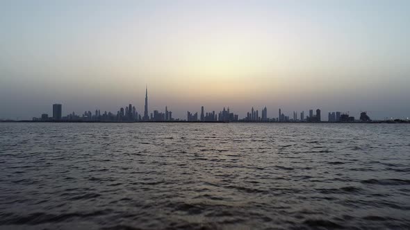 Aerial view at water level of Dubai skyscrapers and bay at sunset, UAE.