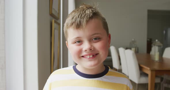 Portrait of caucasian boy smiling while standing in the living room at home