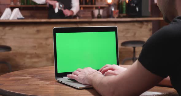 Young Man in Casual Clother Types Fast on a Laptop with Green Screen