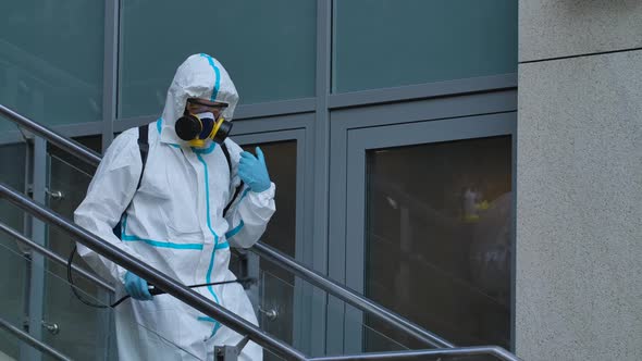 Man in Protective Suit Disinfects Street with an Antiseptic Sprayer. Surface Treatment Due To