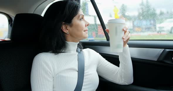 Woman sitting in car holding disposable cup