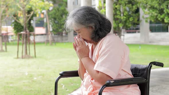 Asian elderly woman in a wheelchair She was hospitalized and coughed up blood.