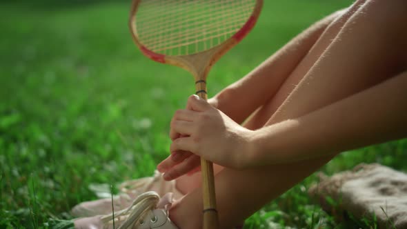 Closeup Girl Legs Hand Holding Badminton Racket in Park