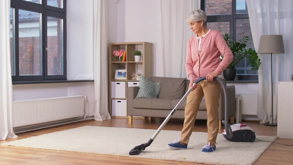 Senior Woman with Vacuum Cleaner Cleaning at Home