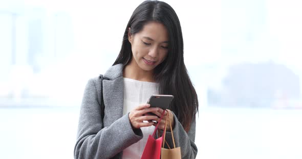 Woman use of smart phone and holding shopping bag