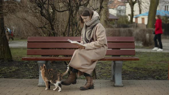 Young Female Reading A Book With Cat