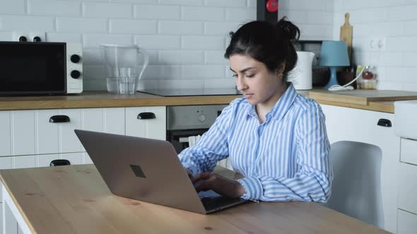 Happy overjoyed young indian business woman celebrating success in home