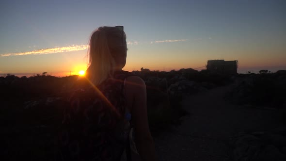 Slowmotion of a Young Blonde Woman walking on Top of Table Mountain during Sunset Revealing the Ligh