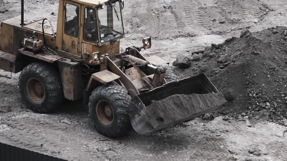 An Old Bulldozer on Rubber Wheels Works on Construction Site