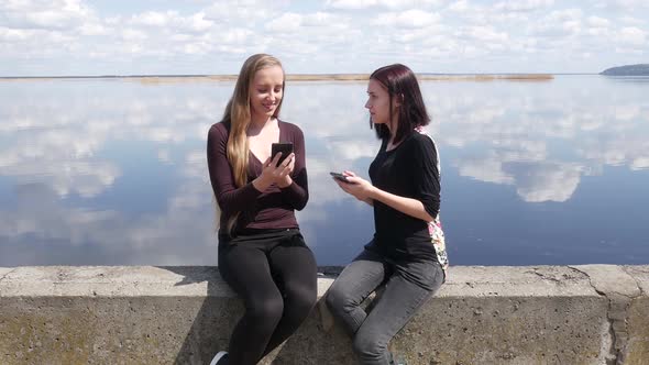 Beautiful Girlfriends Are Sitting On The River Bank