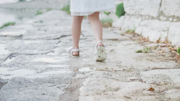 Legs of the Little Girl Walking on the Stones