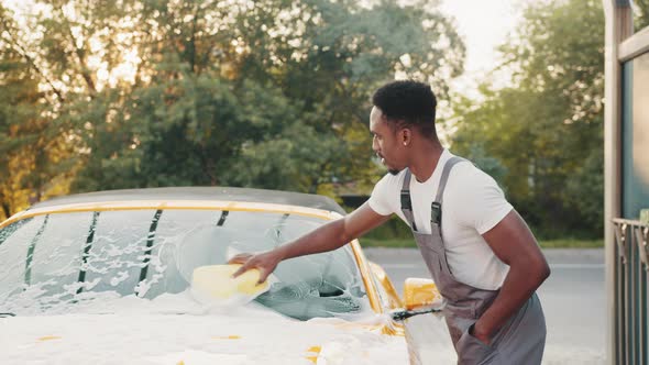 Young Attractive African American Man Washing His Yellow Luxury Car in a