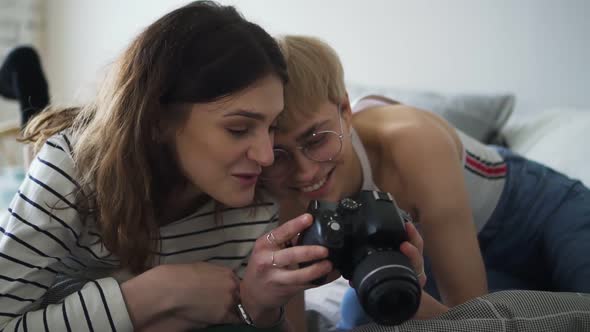 Portrait of Young Homosexual Couple Using Camera While Lying on Bed in Bedroom