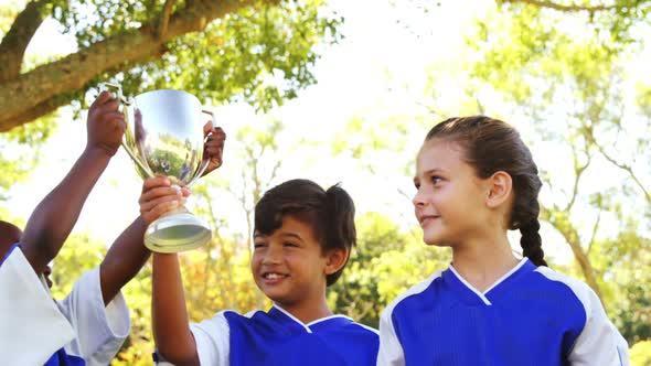 Girl showing trophy to her friends